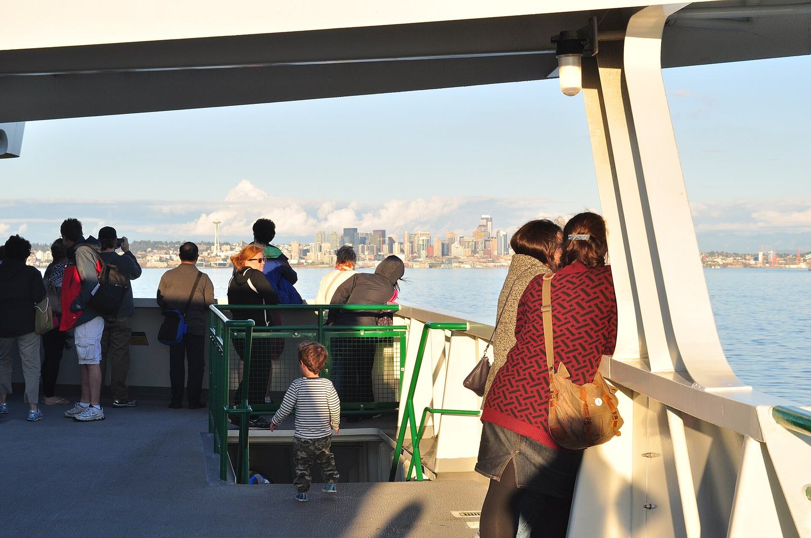 Passengers on the stern deck of a ferry watching the Seattle skyline