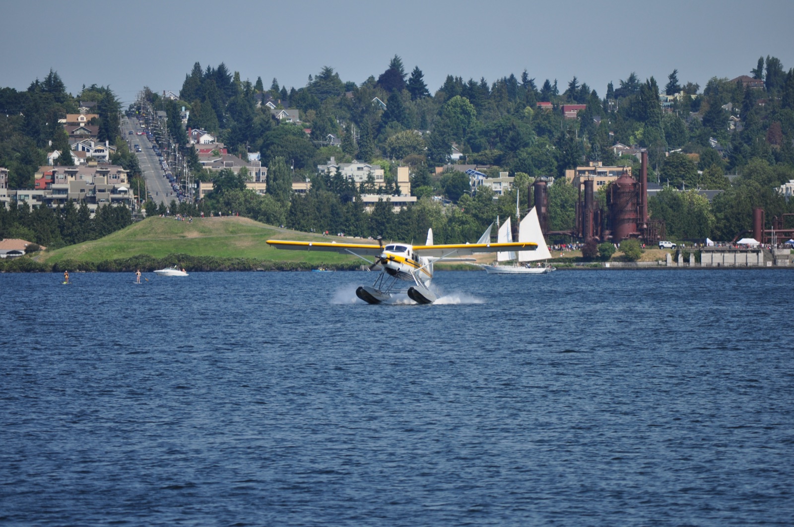 A Kenmore Air floatplane landing on Lake Union with Gas Works Park behind